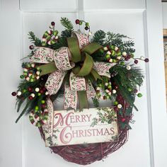 a christmas wreath hanging on the front door with merry christmas sign and holly berry berries