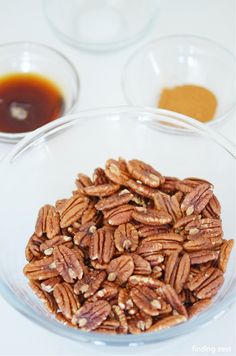 pecans in a glass bowl next to sauces and condiments on a white table