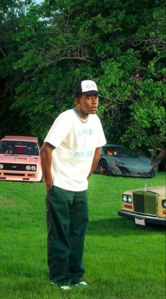 a man standing in the grass next to a car