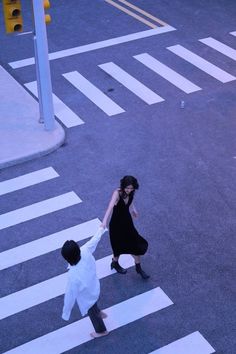 an aerial view of two people crossing the street with their hands in each other's pockets