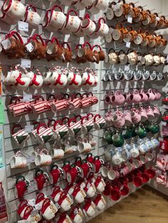 there are many cups and mugs hanging on the wall in this store that is decorated for christmas