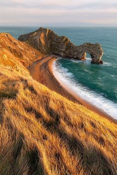 the beach is next to an arch shaped rock formation