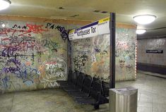 several urinals are lined up against a wall with graffiti on it in a public restroom