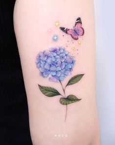 blue hydrangea tattoo on the left arm with butterfly and stars above it,