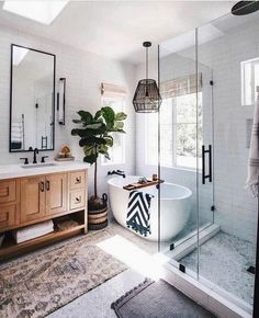 a white bath tub sitting next to a bathroom sink under a large mirror on top of a wooden cabinet