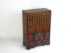 Amazing antique wooden Asian apothecary with 25 drawers with Chinese carvings and small brass rings and a small door on the bottom decorated by brass fittings.  Made out of solid wood, this spice chest is definitely and eye catcher and useful at the same time. In good antique condition with scratches and traces of use overall. There is also some paint/stains on one side of the cabinet. Please see pictures for all details. Measurements: Height: 29.9 inches (76 cm) Length (largest part): 21 inches