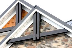 the corner of a brick building with metal roofing and white trim on it's windows