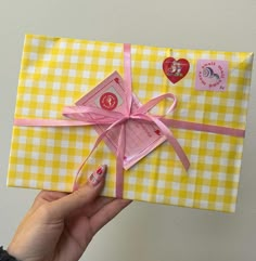 a person holding up a yellow and white checkered wrapping paper with pink ribbon on it