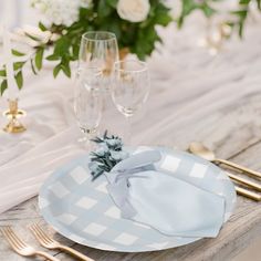 the table is set with white and blue plates, silverware, and gold cutlery