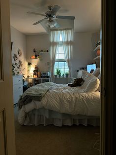 a bed room with a neatly made bed and a ceiling fan in it's corner