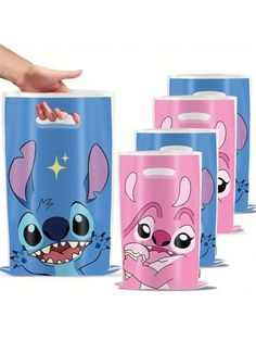 five different colored paper bags with cartoon characters on the front and sides, one being held up by a person's hand