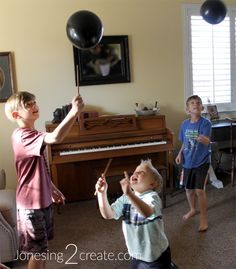 two young boys are playing with balloons in the living room while another boy is watching