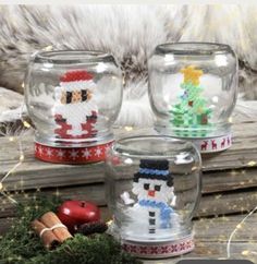 three snow globes sitting on top of a wooden table next to a christmas tree