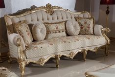 an ornately decorated couch sits in the middle of a room with two lamps on either side