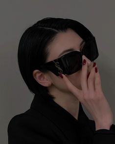 a woman with black hair and sunglasses covers her face