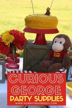 the curious george party supplies are set up with stuffed animals and decorations for an outdoor birthday party