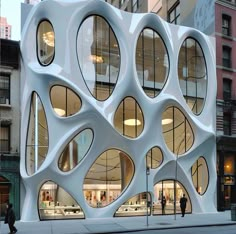 a building with many circular windows on the side of it and people walking in front