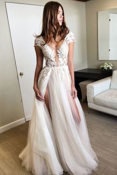 a woman in a white dress is standing near a couch and looking at the camera