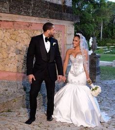 a bride and groom holding hands in front of a stone building