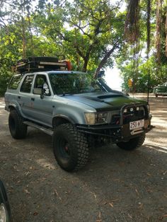 a pick up truck parked on the side of a road in front of some trees