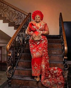 a woman in a red and gold dress standing on some stairs with her arms crossed