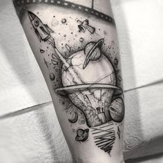 a man's leg with an astronaut themed tattoo on his arm, and space shuttles in the background