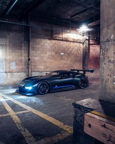 a blue sports car parked in an empty parking garage with no one around it and lights on