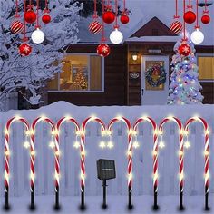 lighted candy canes on poles in front of a house with christmas decorations and lights