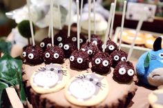 a cake with chocolate frosting and decorated animals on it, sitting in front of other desserts