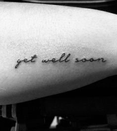 a tattoo saying get well soon on someone's left arm and the word is written in cursive font