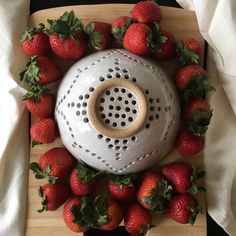 strawberries surround a ceramic grater on a cutting board