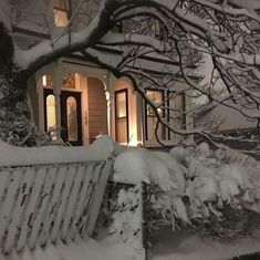 a white bench sitting in front of a house covered in snow