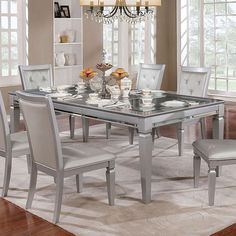 a glass dining table with white chairs around it