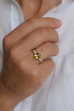 a woman's hand wearing a yellow and green ring with three stones on it