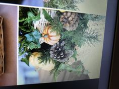 a photograph of pine cones, pumpkins and greenery is displayed on a wall