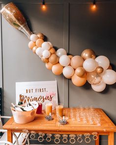 balloons are hanging from the wall above a table with champagne glasses and wine glasses on it