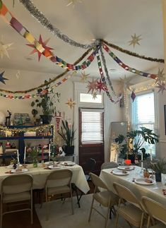 a room filled with tables and chairs covered in paper stars hanging from the ceiling above them