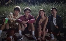 four young people sitting on the ground at night