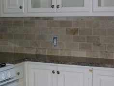 a kitchen with white cabinets and tile backsplash