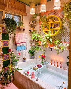 a bathtub with plants and candles in it next to a window filled with potted plants