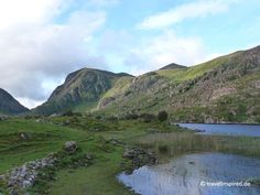 the mountains are covered in green grass and water