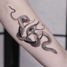 an arm with a snake and eye tattoo on the left side of it, in black ink