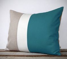 a blue and beige pillow sitting on top of a wooden table next to a white wall