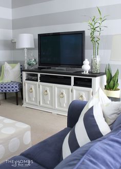 a living room with a large television on top of a white entertainment center next to a blue couch