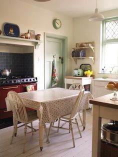 a table and chairs in a small kitchen with an oven on the wall behind it