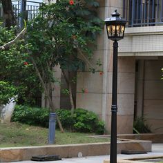 a lamp post on the sidewalk in front of a building with balconies and trees