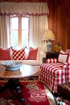 a living room with red and white checkered couches, coffee table and lamp