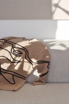 a blanket on the back of a couch with sunlight coming in through it's window