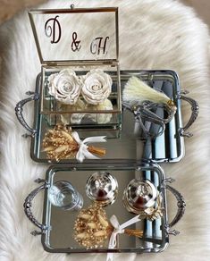 two metal trays with flowers and other items on them sitting on a fur rug