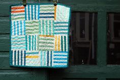 a colorful quilt hanging on the side of a green door with a window behind it